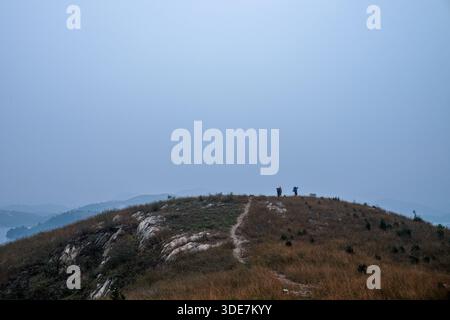 WUHAN, CINA - 31 OTTOBRE 2014: Ampia vista panoramica della cresta montuosa del Longwangjian ricoperta di erba secca autunnale. Piccole figure di escursionisti possono essere viste Foto Stock