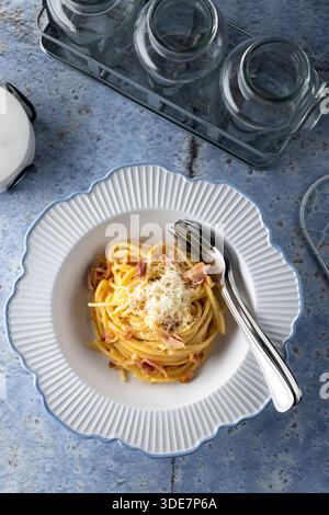 Pasta alla Carbonara con pancetta e parmigiano su un piatto bianco con forchetta Foto Stock