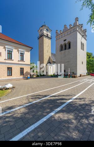 Storico campanile e torre fortificata in piedi a Namestie Svateho Egidia, Poprad sotto un cielo azzurro Foto Stock