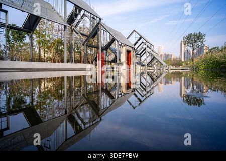 WUHAN, CINA - 17 SETTEMBRE 2015: Ampia vista del giardino a tema industriale con strutture in acciaio scheletriche su una piscina riflettente presso il WUH Foto Stock