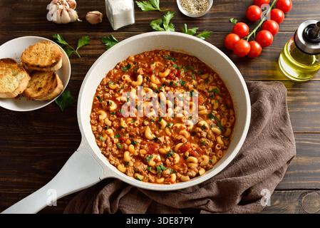 Gulasch americano, piatto con carne macinata, verdure e pasta in salsa di pomodoro in teglia di cottura su un tavolo di legno. Vista ravvicinata Foto Stock