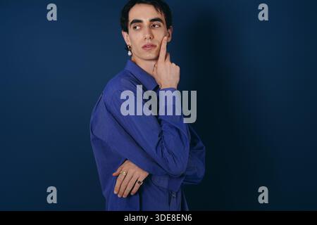 Il raffinato abito in un'elegante camicia blu crea una posa attenta e un fascino che trasuda. Foto Stock