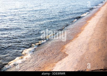 Onde azzurre tempestose con schiuma marina che si frantumano sulla lastra di cemento, vista della struttura del mare direttamente sopra il tramonto Foto Stock