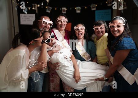 Un gruppo di donne sta posando per una foto con gli occhiali da sole. Una donna sta tenendo in braccio un bambino Foto Stock