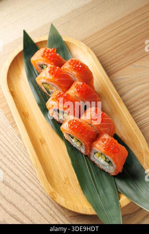 Coloratissimi sushi ripieni di verdure e pesce seduti su un piatto di bambù. Il piatto è caratterizzato da uova di salmone sulla parte superiore, evidenziando il tradizionale tipo giapponese Foto Stock