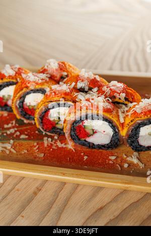 Un piatto di legno offre vivaci sushi roll ripieni di pesce e verdure. I fiocchi decorano la parte superiore, migliorando la presentazione del piatto durante una cena Foto Stock