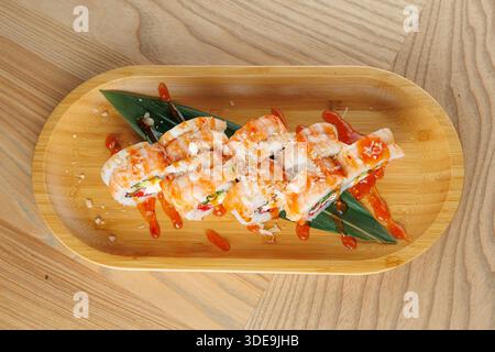 Gli involtini di sushi sono disposti ordinatamente su un piatto di bambù con una salsa vibrante e guarnigioni. Questa scena cattura l'essenza della cucina giapponese in un Foto Stock