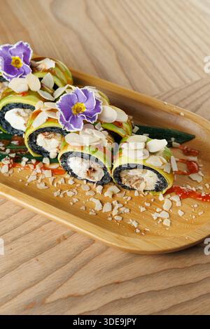 Panini di sushi ripieni di pesce seduti su un vassoio di bambù Condito con fiori e mandorle affettate, il piatto presenta una presentazione colorata e un ingre fresco Foto Stock