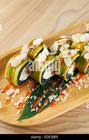 Panini di sushi preparati con avocado fresco e ricoperti da fette di mandorle, sistemati su un vassoio di bambù Condito con salsa, questo piatto mostra lo sci culinario giapponese Foto Stock