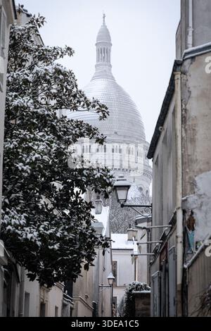 La basilica del Sacro cuore di Montmartre è visibile durante la forte tempesta di neve che ha colpito Parigi. Una forte tempesta di neve ha colpito la capitale francese, causando molta eccitazione tra parigini e turisti , ma anche un sacco di disagi nei trasporti su strada. Vicino alla Basilica del Sacro cuore nel quartiere di Montmartre, la gente scivola giù dalla collina sulla neve. Foto Stock