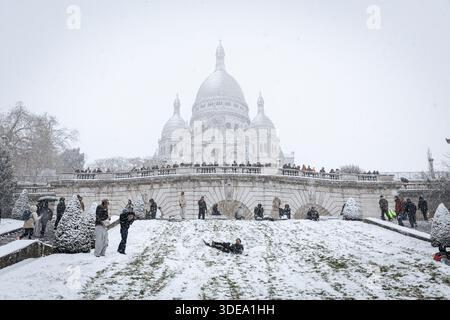 Vicino alla basilica del Sacro cuore di Montmartre si vedono persone durante la tempesta di neve che ha colpito Parigi. Una forte tempesta di neve ha colpito la capitale francese, causando molta eccitazione tra parigini e turisti , ma anche un sacco di disagi nei trasporti su strada. Vicino alla Basilica del Sacro cuore nel quartiere di Montmartre, la gente scivola giù dalla collina sulla neve. Foto Stock