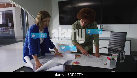 Uomo pendente con camicia verde e donna blu-blazer che srotola e allinea i piani in ufficio, con icone AR Foto Stock