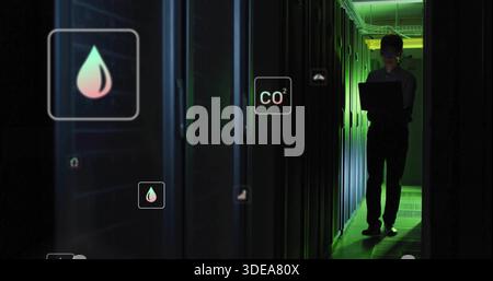 Monitoraggio della tecnologia coreana a maniche lunghe che tiene il laptop nella corsia del server, icone dell'ologramma, spazio di copia Foto Stock