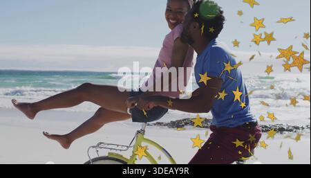 Coppia in sella a una bicicletta lungo la costa, top rosa donna, camicia blu uomo, stelle dorate Foto Stock