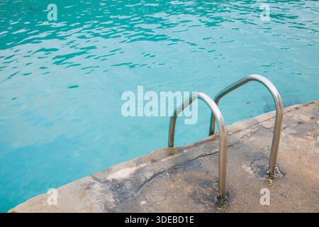 Scala metallica per piscine che conduce all'acqua di mare turchese nella baia di Cala Santanyi a Maiorca, Spagna. Primo piano di acqua cristallina. Foto Stock