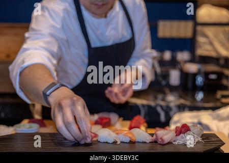 Lo chef sushi prepara meticolosamente sashimi freschi al sushi bar in un esclusivo ristorante giapponese. Foto Stock