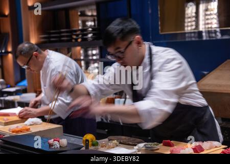 Chef di sushi che preparano sashimi freschi al sushi bar in un esclusivo ristorante giapponese. Foto Stock