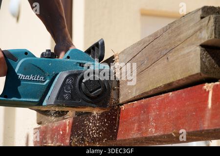 Viaggia in romania transilvania targu mures persona utilizzando una motosega elettrica per la lavorazione del legno, creando segatura Foto Stock
