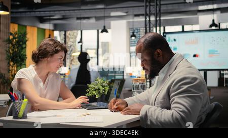Candidato di sesso nero che firma i documenti e riceve l'approvazione per l'onboarding, entusiasta di una nuova posizione commerciale. Job seeker e recruiter finalizzano il processo di assunzione con questioni legali. Telecamera A.. Foto Stock