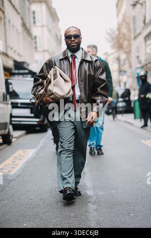 Parigi, Francia – 11 marzo 2025: Un ospite che indossa una pelle oversize marrone con occhiali da sole durante la Paris Fashion Week. Foto Stock