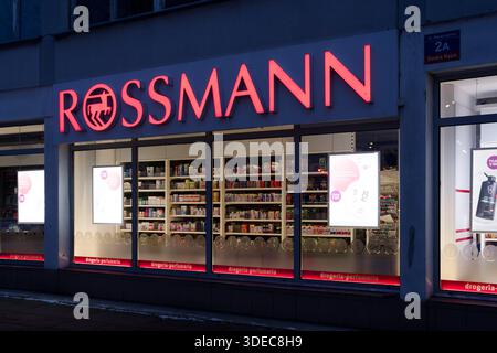 L'esterno della farmacia Rossmann illuminata di notte con esposizione dei prodotti visibile attraverso le finestre, la zona urbana di vendita al dettaglio in inverno. Foto Stock