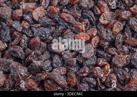 Vista macro, uvetta illuminata dal sole luccicante, lucentezza umida e sfumature marroni variegate, gruppi ben confezionati che creano un'atmosfera da snack naturale dalla consistenza ricca, salutare Foto Stock