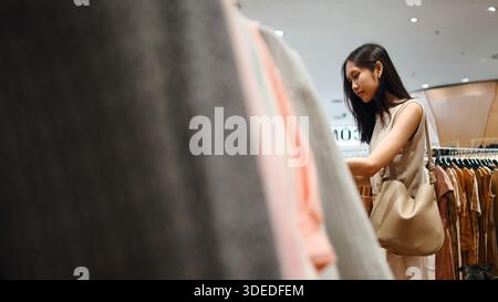 Donna thailandese che fa shopping al negozio di abbigliamento con il cane, scegliendo nuovi capi di abbigliamento Foto Stock