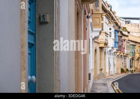 Strada stretta fiancheggiata da tradizionali balconi maltesi ed edifici residenziali storici a Sliema, Malta, il 28 dicembre 2024, che mostra l'urba di tutti i giorni Foto Stock