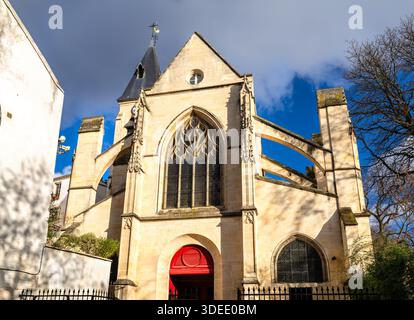 La Chiesa di Saint Medard si trova a Parigi, in Francia. La storica architettura gotica presenta una facciata in pietra con contrafforti volanti e una porta rossa luminosa nelle vicinanze Foto Stock