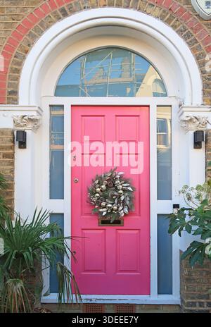 Corona di Natale su una porta d'ingresso rosa brillante di una casa vittoriana nel sud di Londra, Regno Unito. Foto Stock