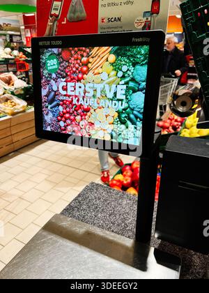 Brno, Repubblica Ceca - 29 novembre 2025: Il luminoso schermo touchscreen Kaufland al check-out mostra un colorato collage di prodotti in un supermar affollato Foto Stock