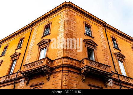 Una vista ravvicinata di uno storico edificio arancione con dettagli architettonici ornati, caratterizzato da balconi e finestre Foto Stock