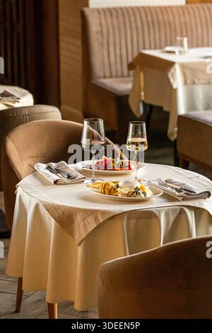 Accogliente tavolo del ristorante con bicchieri da vino e piatti Foto Stock