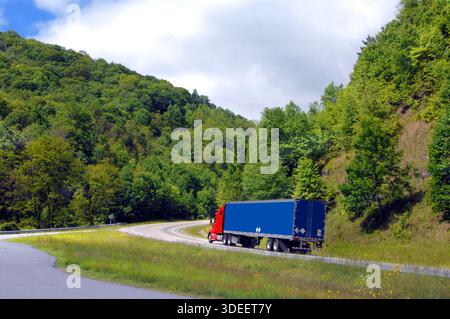 Diciotto ruote lo mette in marcia bassa per farlo intorno alla curva e su la ripida montagna Appalachian. La cabina è rossa e il rimorchio è blu chiaro. Foto Stock