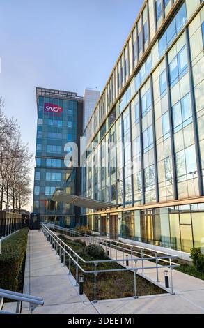 Saint-Denis, Francia - 29 dicembre 2025: L'edificio della sede centrale del gruppo SNCF si trova presso il Campus Etoiles. La moderna architettura in vetro presenta la rai francese Foto Stock