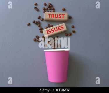 Simbolo dei problemi di fiducia. Blocchi di legno con parole problemi di fiducia. Splendido sfondo grigio con tazza di caffè e chicchi di caffè. Business and Trust Issues conc Foto Stock