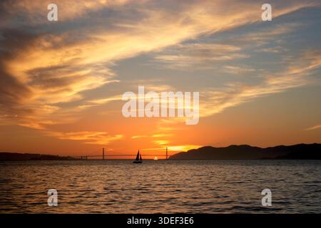 Silhouette di una barca a vela che passa davanti al Golden Gate Bridge al tramonto, San Francisco, California, Stati Uniti Foto Stock