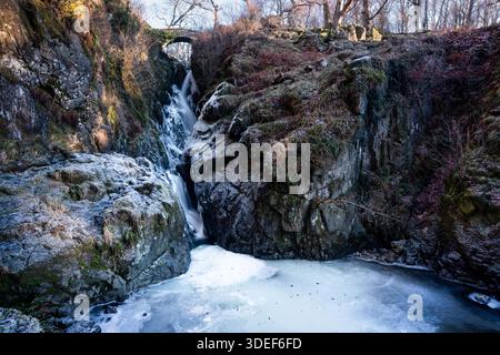 Cascata Aira Force vicino a Ullswater, Lake District, Cumbria, Inghilterra. Rocce ricoperte di ghiaccio e un Aira Beck parzialmente congelato in una giornata invernale molto fredda Foto Stock