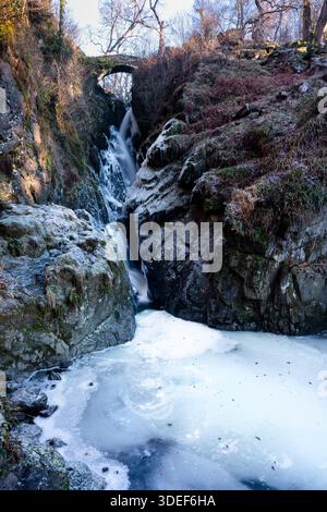 Cascata Aira Force vicino a Ullswater, Lake District, Cumbria, Inghilterra. Rocce ricoperte di ghiaccio e un Aira Beck parzialmente congelato in una giornata invernale molto fredda Foto Stock
