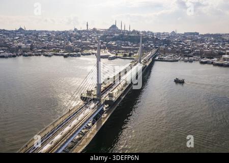 Veduta aerea dello scintillante Ponte della metropolitana del Corno d'Oro che si estende sull'acqua, con le sagome di Santa Sofia e della Moschea Blu che abbelliscono il cielo Foto Stock