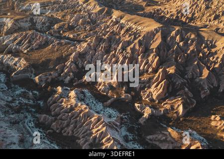Vista aerea delle affascinanti formazioni rocciose che gettano lunghe ombre sotto la luce dorata del paesaggio surreale della Cappadocia, Cappadocia, Turkiye. Foto Stock