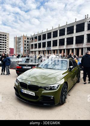 Ternopil, Ucraina - 29 novembre 2025: Berlina BMW 3 serie F30 verde oliva tra la folla a un salone di auto all'aperto con lo sfondo di un edificio incompiuto. Foto Stock