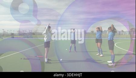 Quattro atlete che tengono le braccia sul campo in erba, con maglie blu e bianche, si stendono nelle vicinanze Foto Stock