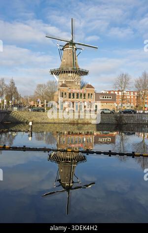 Il tradizionale mulino a vento olandese De Gooyer e Brouwerij 't IJ ad Amsterdam, Paesi Bassi, si riflette in un canale in una soleggiata giornata invernale. Amsterdam Paesi Bassi, Foto Stock