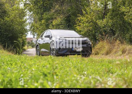 Auto nera su una strada di campagna circondata dal verde nel cielo nuvoloso, auto elettrica VW ID5, Deer e-Carsharing, Calw, Germania Foto Stock