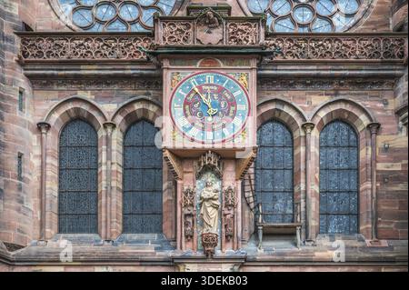 L'orologio astronomico ornato sulla facciata sud della cattedrale di Strasburgo mostra un quadrante colorato con lancette dorate ed è affiancato da sculture gotiche Foto Stock