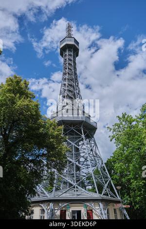 Un'impressionante foto a basso angolo dell'iconica Torre Petrin Lookout di Praga, Repubblica Ceca, ambientata su un cielo blu vibrante con soffici nuvole bianche. Foto Stock