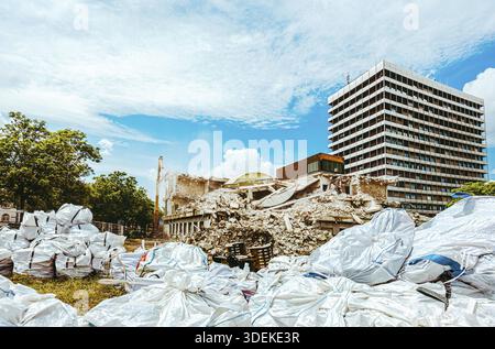 Processo di demolizione di un vecchio edificio smantellato. L'escavatore sta distruggendo la vecchia casa. Distruzione di abitazioni fatiscenti per un nuovo sviluppo. Demolizione di Foto Stock