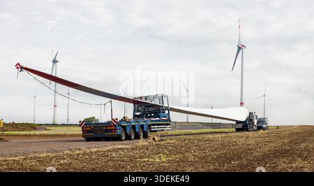 Turbine eoliche in costruzione. Pala per turbine eoliche in primo piano. Trasporto speciale di una pala per una turbina eolica su un semirimorchio speciale Foto Stock