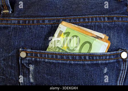 Moneta in euro contanti, banconote in euro nelle tasche dei pantaloni in jeans. Concetto di ricchezza, risparmio o spesa. Le banconote in euro cadono. Facile t Foto Stock